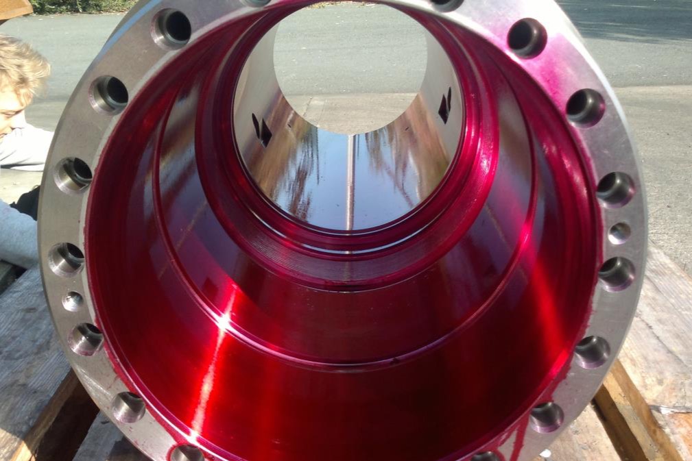 A large machined component with a polished bronze cone, standing on a pallet in the yard.