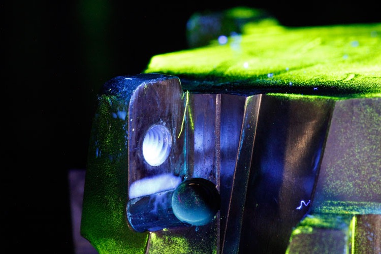 Magnetic particle inspection under ultraviolet light: the edge of a weld glows green.